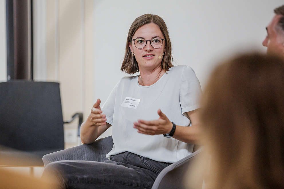 Zu sehen ist eine Frau im Portrait, die bei einer Podiumsdiskussion spricht: Leonie Sontheimer