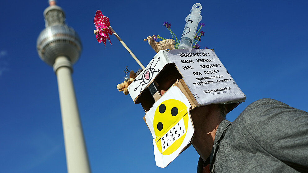 Person mit einem mit politischen Parolen beschrifteten Karton auf dem Kopf