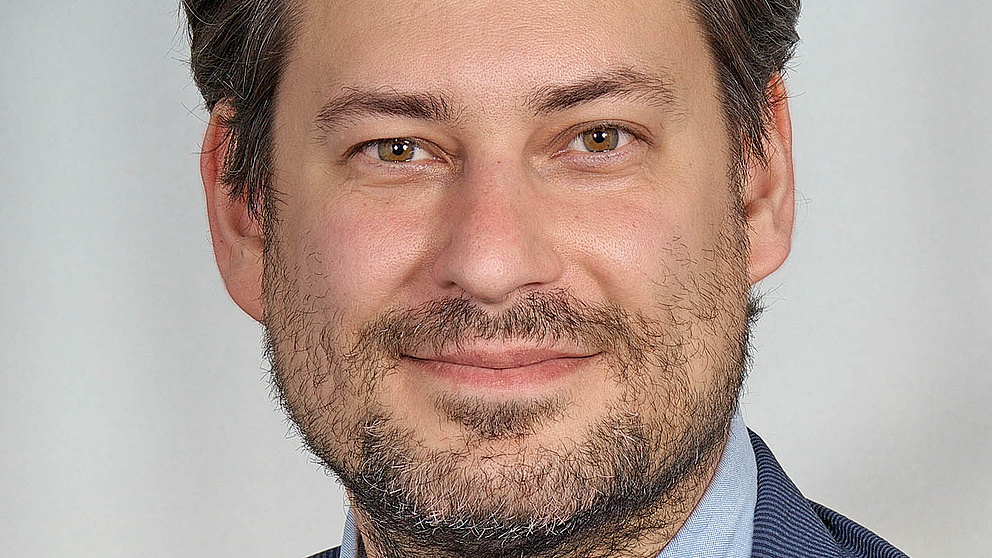 Poatraitbild eines lächelnden dunkelhaarigen Mannes, Michael Laha