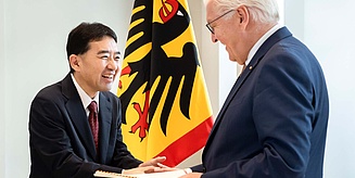 Zwei Männer, lachend bei der Urkundenübergabe