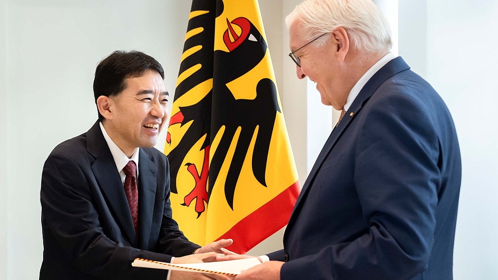 Zwei Männer, lachend bei der Urkundenübergabe 
