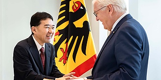 Zwei Männer, lachend bei der Urkundenübergabe 