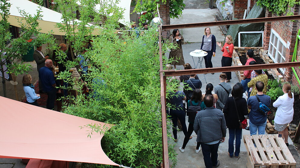 Foto von oben auf die Teilnehmer*innen einer Veranstaltung in einem Garten