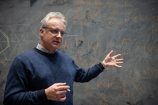 Foto von Robert Raußendorf vor einer Tafel mit mathematischen Formeln