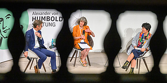 Drei Personen führen ein Gespräch bei einer Veranstaltung der Alexander von Humboldt-Stiftung im Halbkreis arrangiert.