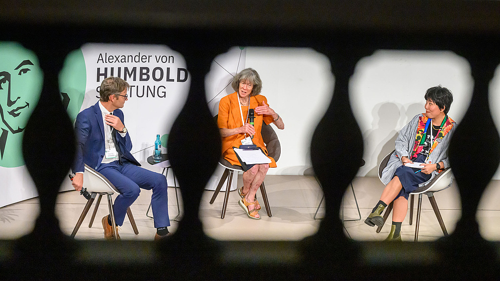 Drei Personen führen ein Gespräch bei einer Veranstaltung der Alexander von Humboldt-Stiftung im Halbkreis arrangiert.
