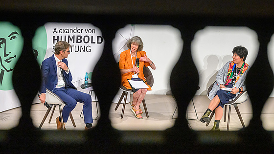 Drei Personen führen ein Gespräch bei einer Veranstaltung der Alexander von Humboldt-Stiftung im Halbkreis arrangiert.