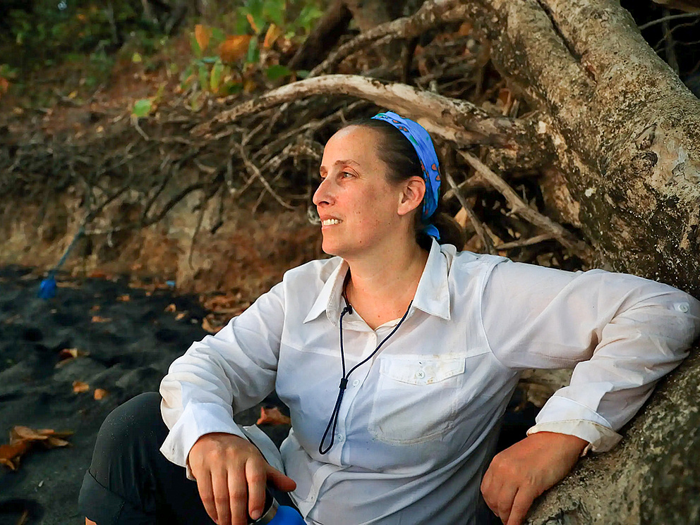 Die Forscherin Meg Crofoot sitzt an einen Baum gelehnt.