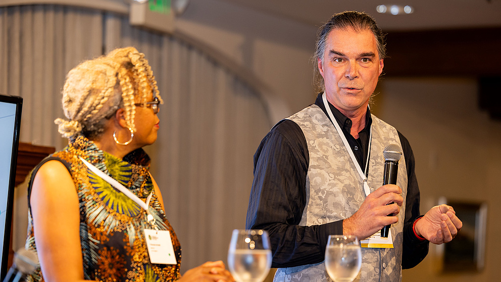 Eine Frau und ein Mann auf einem Podium sprechen miteinander. 