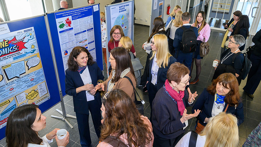 Viele Menschen stehen neben Postern und unterhalten sich. In der Vogelperspektive aufgenommen.