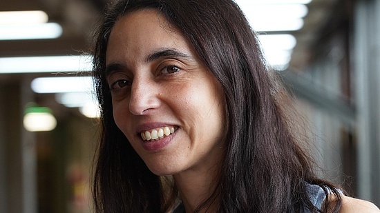 Das Portrait-Foto zeigt Paula Tribelli in der Universität Buenos Aires. Sie hat dunkles, mittellanges Haar und trägt ein hellblaues Oberteil.