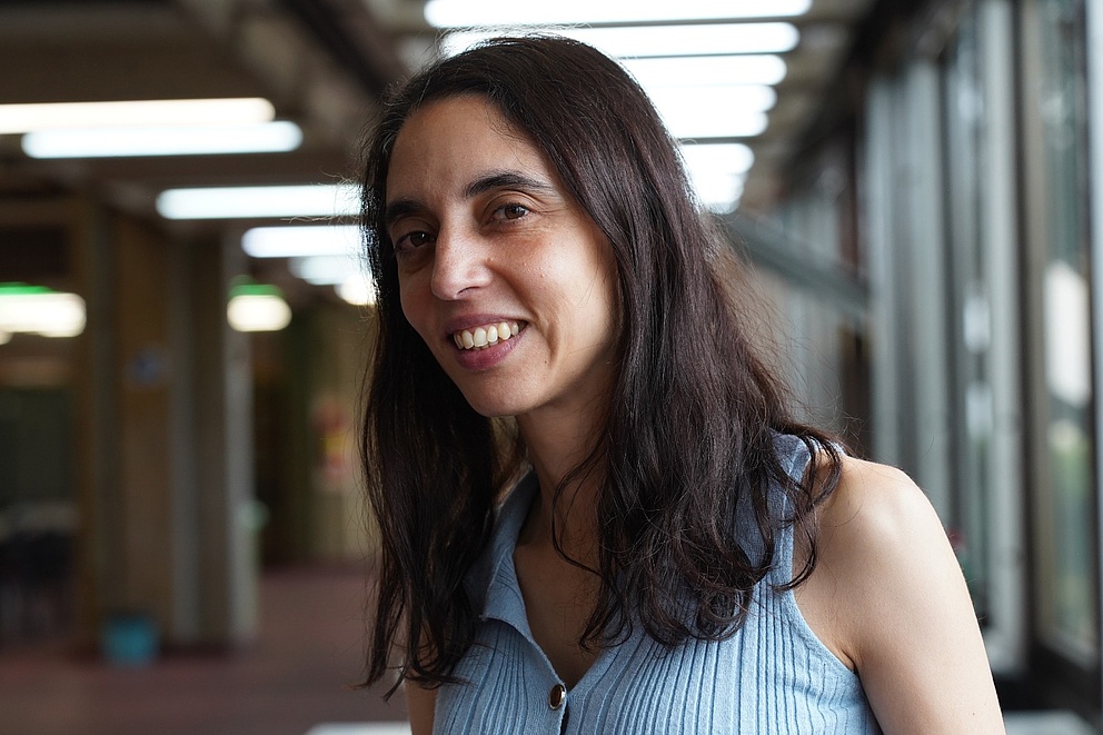 Das Portrait-Foto zeigt Paula Tribelli in der Universität Buenos Aires. Sie hat dunkles, mittellanges Haar und trägt ein hellblaues Oberteil.