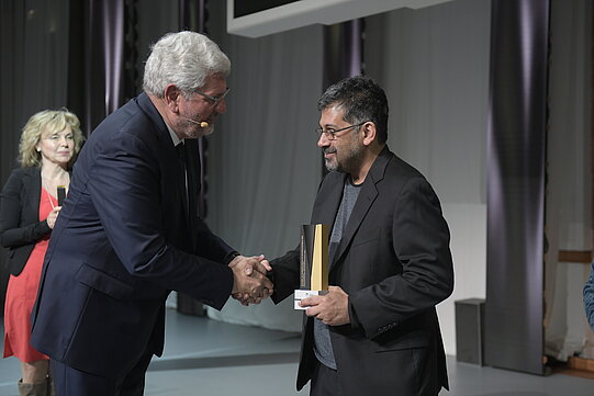Stiftungspräsident Robert Schlögl schüttelt die Hand von Sayan Mukherjee