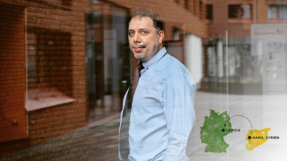 Mahmod Muhsen steht hinter der Glasfassade eines modernen Gebäudes und blickt in die Kamera..
