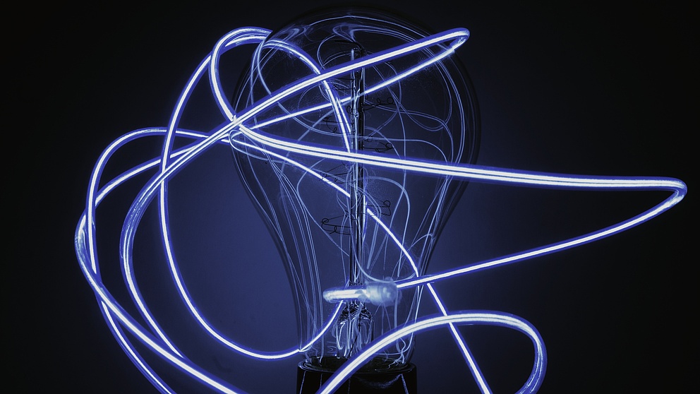 Glühbirne umgeben von dünnen Lichtschläuchen, in dunkelblau gehalten. 