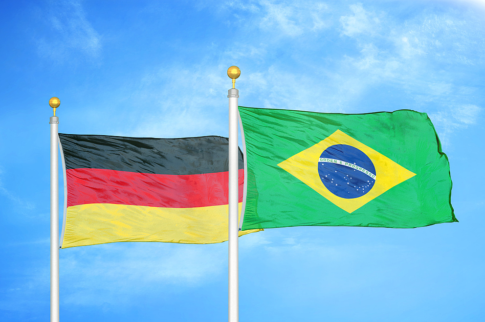 eine deutsche und eine brasilianische Flagge wehen vor einem blauen Himmel