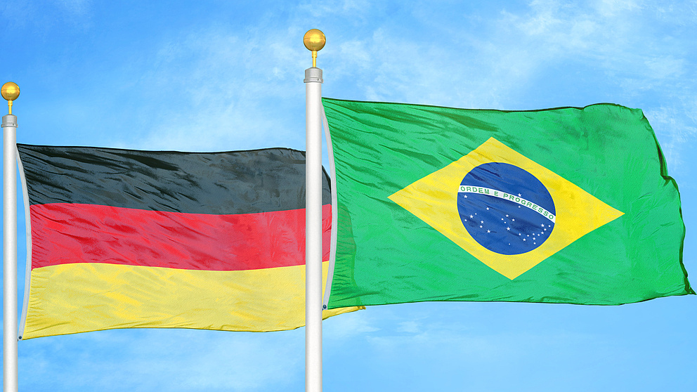 eine deutsche und eine brasilianische Flagge wehen vor einem blauen Himmel