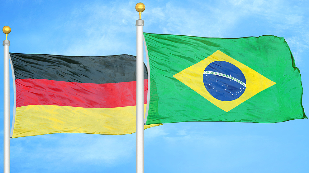 eine deutsche und eine brasilianische Flagge wehen vor einem blauen Himmel