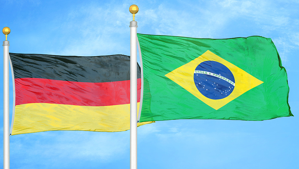 eine deutsche und eine brasilianische Flagge wehen vor einem blauen Himmel
