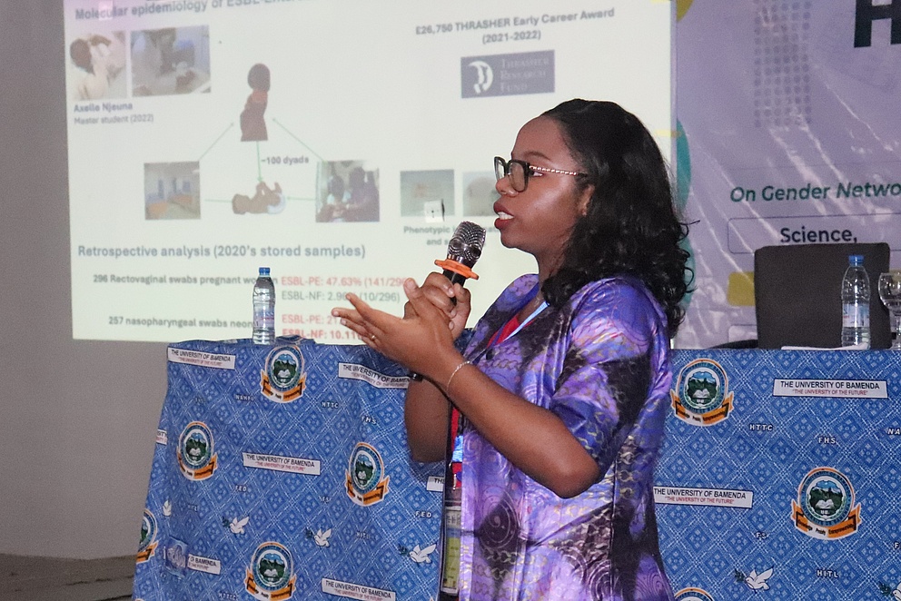Das Bild zeigt die Keynotespeakerin Luria Founou, wie sie mit einem Mikrofon in der Hand einen Vortrag hält.