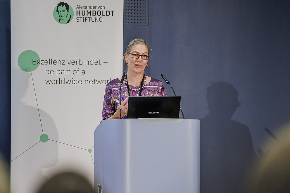 Eine Frau steht hinter einem Rednerpult, es handelt sich um Anke Reiffenstuel