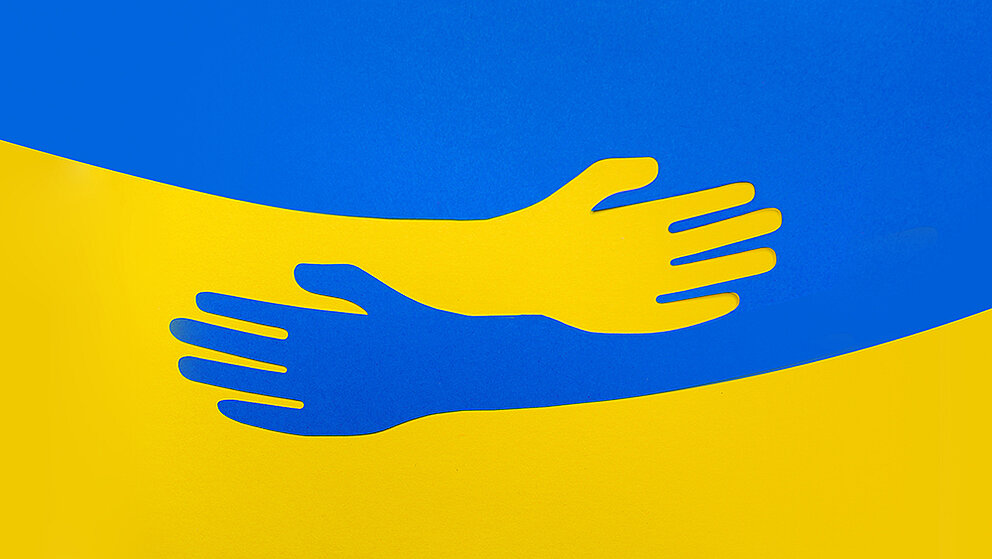Ukraine-Flagge und zwei sich umarmende Hände.
