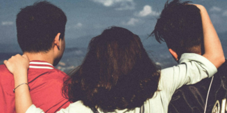 Bild mit einer Frau und zwei Männern, die sich umarmen und von hinten zu sehen sind. Sie schauen in die Ferne. Auf dem Bild steht grün unterlegt: Join te DAAD and Humboldt Community. Unten sieht man das Logo der Community.