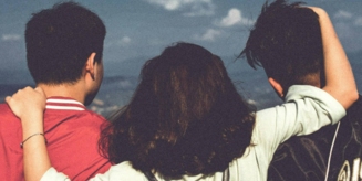 Bild mit einer Frau und zwei Männern, die sich umarmen und von hinten zu sehen sind. Sie schauen in die Ferne. Auf dem Bild steht grün unterlegt: Join te DAAD and Humboldt Community. Unten sieht man das Logo der Community.